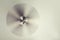 A working ceiling fan on a white ceiling, close up with blurred fan blades, three lamps, daytime.