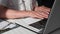 working at computer, young woman is typing on a laptop keyboard while sitting at a table, a close-up