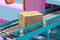 Working conveyor roller with blank cardboard box at factory in Pink and blue pastel colors. 3d rendering.