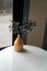 Working corner decorated with mustard color ceramic vase with artificial plant inside white marble working table in natural light