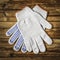 Working cotton gloves on brown wooden background.