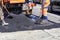 The working crew evenly distributes hot asphalt with shovels manually on the repaired site of the road