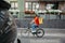 Working day courier in city. Young man in safety helmet with backpack rides on bicycle at road