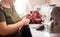 Working female hands using scissors for cutting off plaid fabric in sewing process. Close up view. Blurred background.