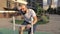 Working hard. Muscular bald man trains on a stationary bike on the street sports ground in a beautiful city park in