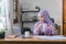 Working from home, a Muslim millennial woman in a purple hijab appears worried, tired, and overwhelmed while using her