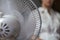 A working household fan on the table and a blurry image of the girl in the background