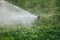 Working lawn sprinkler spraying water over green grass