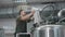 A working male brewer pours crushed malt into a beer tank to produce craft beer. Close-up