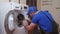 Working man plumber repairs a washing machine in home. Washing machine installation or repair. plumber connecting
