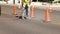 Working man uses a jackhammer on the asphalt of a city street next to the orange safety warning cones, as part of a utility
