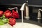 Working mixer tap with a few roses on a counter