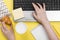 Working morning. Girl works for laptop. Breakfast at work - cappuccino, croissant, notebook on yellow background. Top view