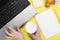 Working morning. Girl works for laptop. Breakfast at work - cappuccino, croissant, notebook on yellow background. Top view