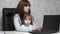 Working mother with her little daughter at the table. Busy woman working on laptop with baby on hands. Working mom with