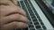 Working online on the keyboard of a laptop. Stock footage. Close up of male hands typing text on the keyboard, pressing