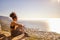 Working out indoors is just not as rewarding. a young woman looking at the view while sitting on a mountain cliff.