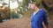 Working out in the park. Young woman in blue jacket gets ready for running stretching her arms and legs in beautiful