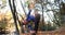 Working out in the park. Young woman in blue jacket gets ready for running stretching her arms and legs in beautiful