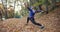 Working out in the park. Young woman in blue jacket gets ready for running stretching her arms and legs in beautiful