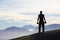 Working out with a view. Rearview of a man standing on a mountain top holding dumbells.