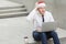 Working in outdoor, sits on the ground. Young adult ginger bearded businessman in santa hat, work in pc and dreaming.