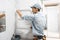 Working plumber mounts a new chrome-plated heated towel-type coil on the wall of tiles