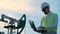 Working process of a male worker holding a laptop next to a functioning gas derrick. Energy, oil, gas, fuel pumping rig.