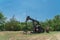 Working pump jack pumping crude oil at oil drilling site in rural USA