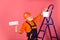 Working in repair shop. senior man painter use roller on ladder. painting the wall in pink. professional painter in