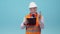 Working specialist man in a helmet, vest and glasses with headphones transmits on the radio text written on a paper