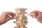 Working team concept: two men`s hands positioning wood blocks in a tower made with wooden blocks with clipping path and copy spac