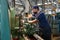 A working turner wearing a protective antiviral mask sets up the machine at the factory