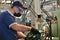 A working turner wearing a protective antiviral mask sets up the machine at the factory