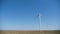 Working twisting windmills stand in a field in summer