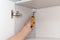 A workman fixing cabinet with screwdriver in kitchen.