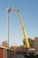 Workman in an hydraulic hoist repairing installation of a high telephonemast