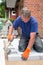 Workman laying new paving stones for a patio.