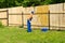 Workman paints wooden fence with a paint roller