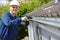 Workman Replacing Guttering On Exterior Of House