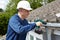 Workman Replacing Guttering On Exterior Of House