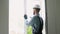 Workman in uniform installing or adjusting plastic windows in the living room at home