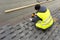 Workman using pneumatic nail gun install tile on roof of new house under construction