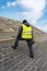 Workman using pneumatic nail gun install tile on roof of new house under construction