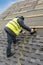 Workman using pneumatic nail gun install tile on roof of new house under construction