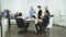 Workmates sit at a table, man stand and congratulate his colleague