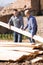 Workmen arranging building timber at farm