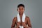 After workout. Half teenage african boy with towel on shoulders looking at camera, standing against grey