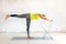 Workout with props. Fit caucasian woman practice yoga balance with one leg up and a chair on a mat in loft white studio