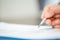 Workplace closeup person professional businesswoman sitting at desk hold pen signing or signature contract paper. Employee woman